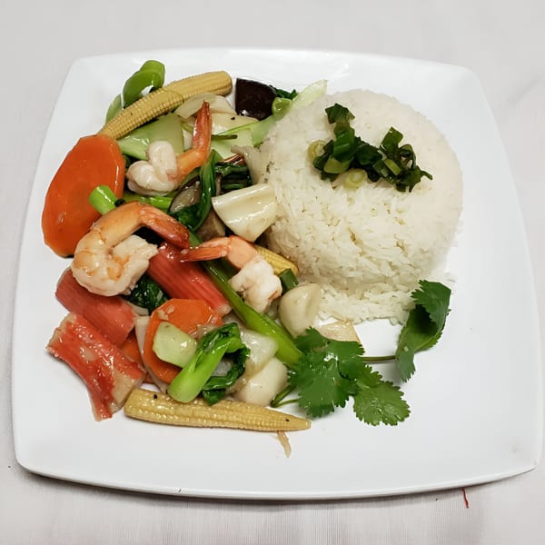 Vietnamese stir-fried seafood and vegetables with white rice, garnished with green onions and cilantro.