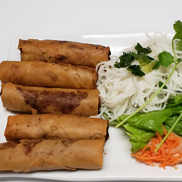 Crispy Vietnamese spring rolls with vermicelli noodles, lettuce, pickled carrots, and cilantro on a white plate.